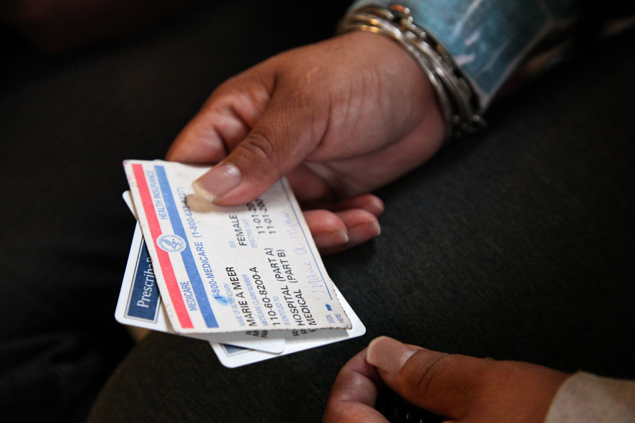 A woman holds medical insurance cards.