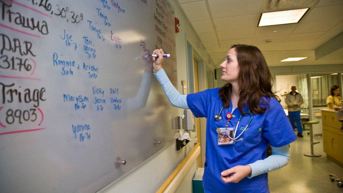 A nurse writes on the wall chart.