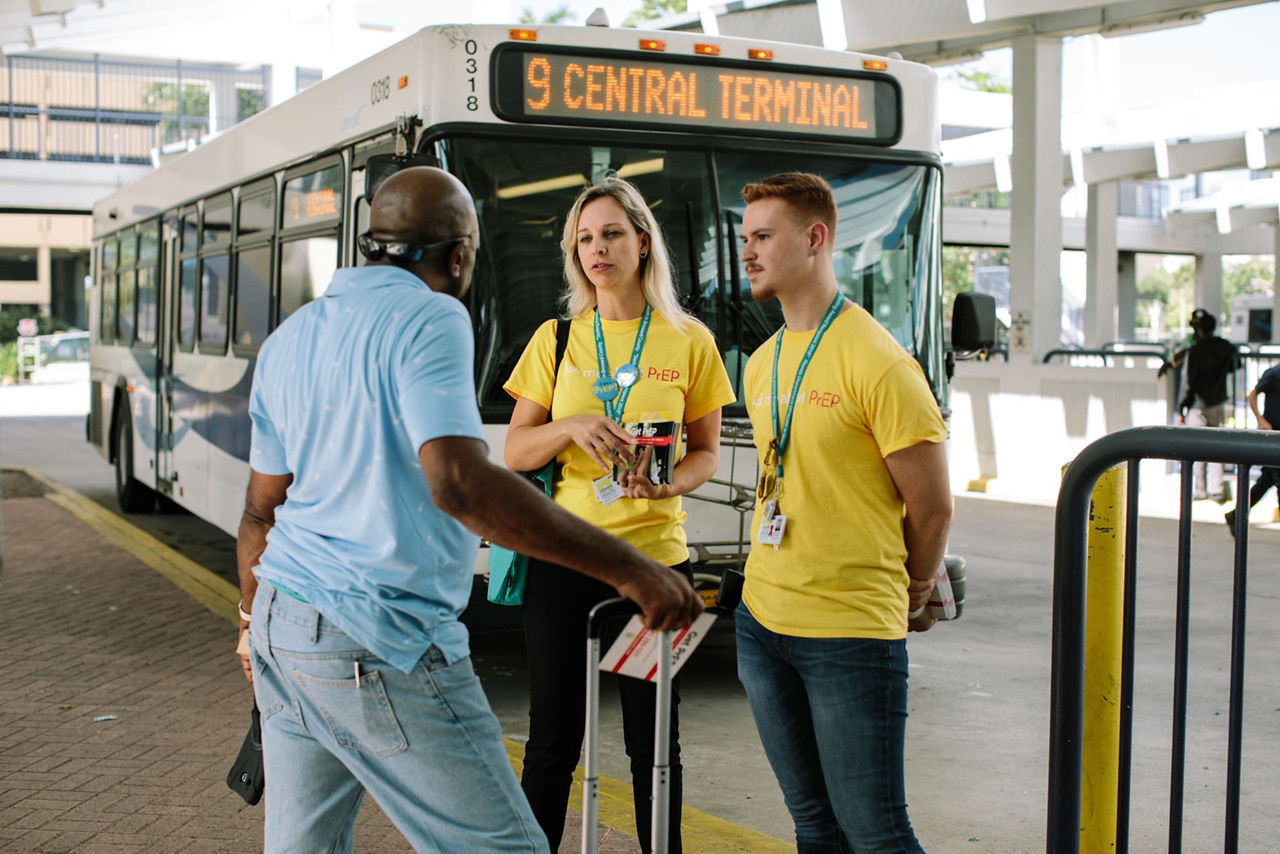 Broward County outreach workers speak with a man at a bus stop.