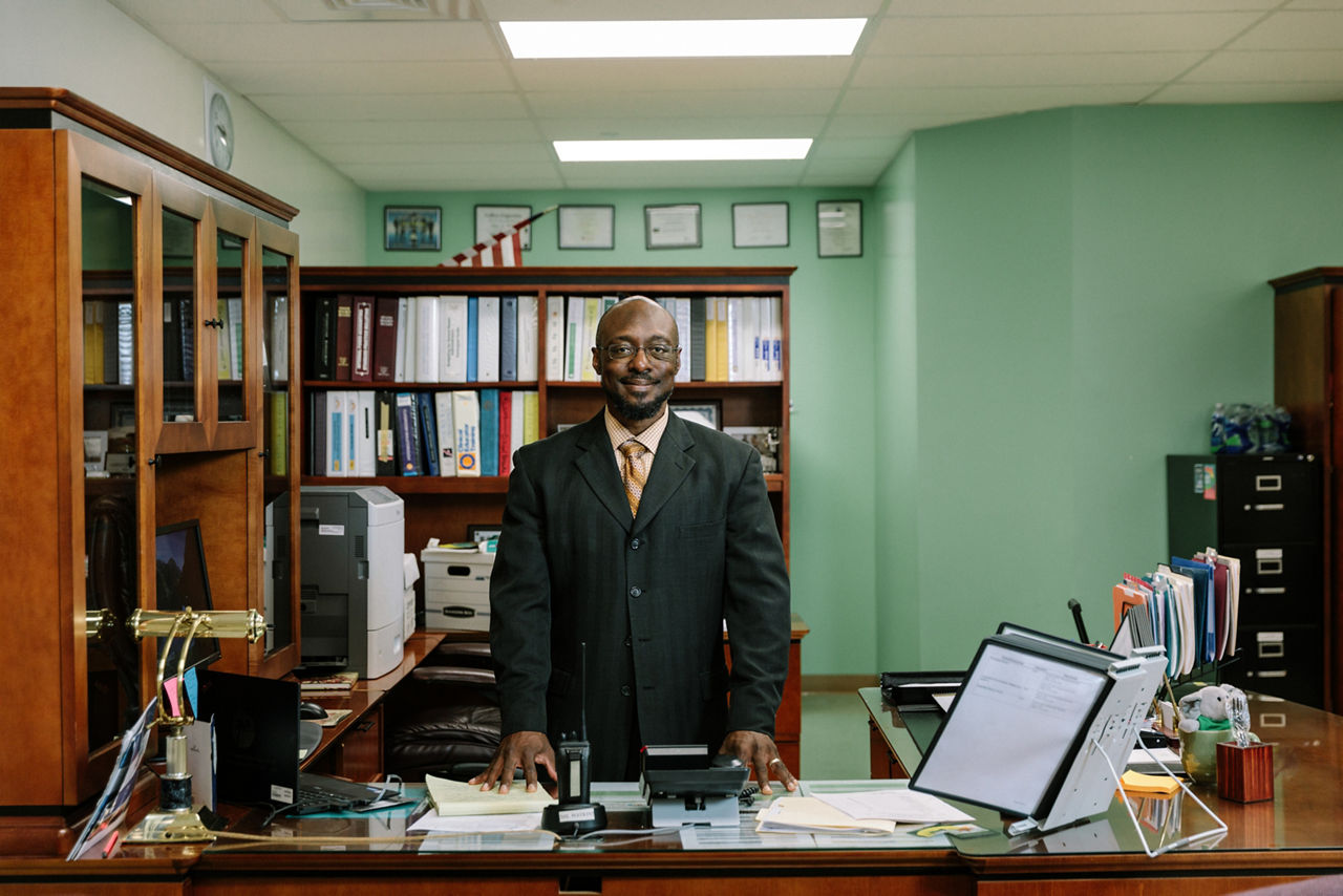 A man standing behind the desk in his office.