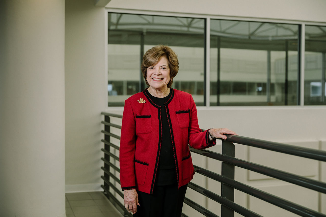 A smiling woman standing in an office hallway.