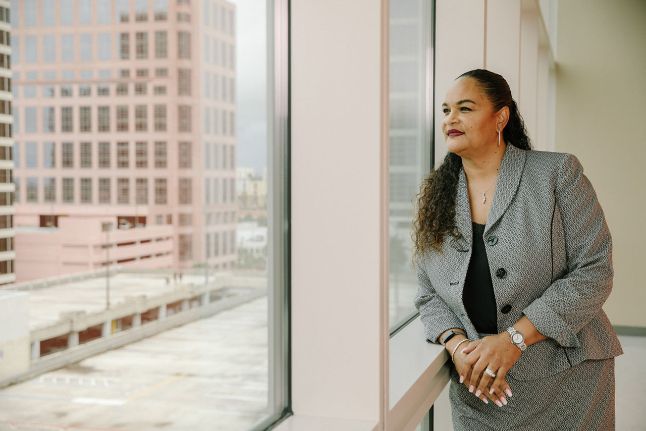 A woman in a suit looking out an office window.