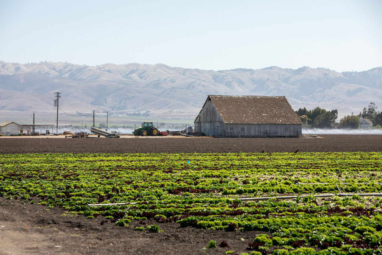 A farm with a barn and mountains in the background. 