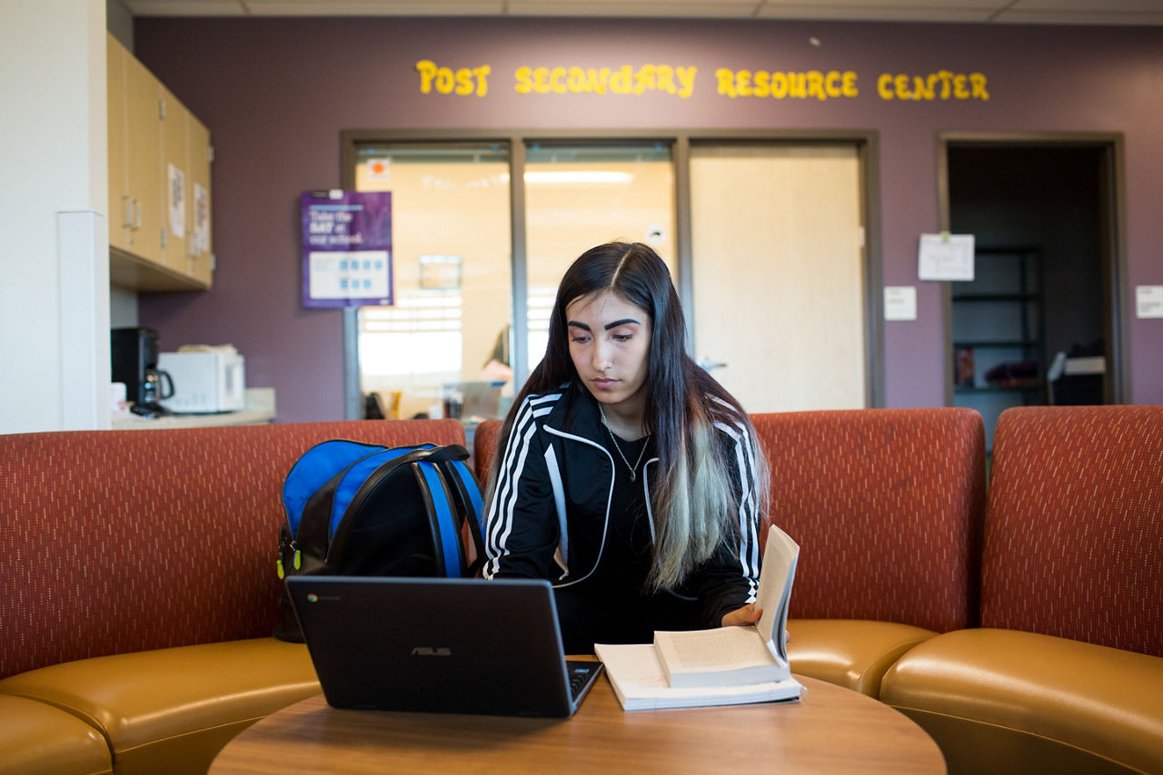 A high school student working on a laptop in a resource center.