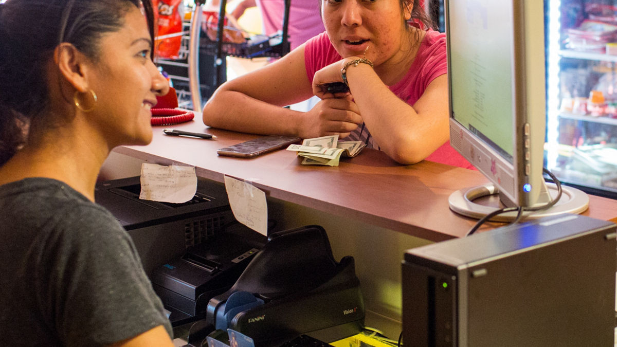 A woman smiles behind a counter at a store. 