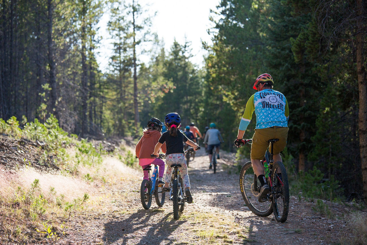 A family riding bicycles through a trail.