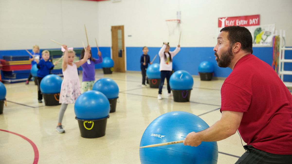 A teacher leads an exercise class for young children.