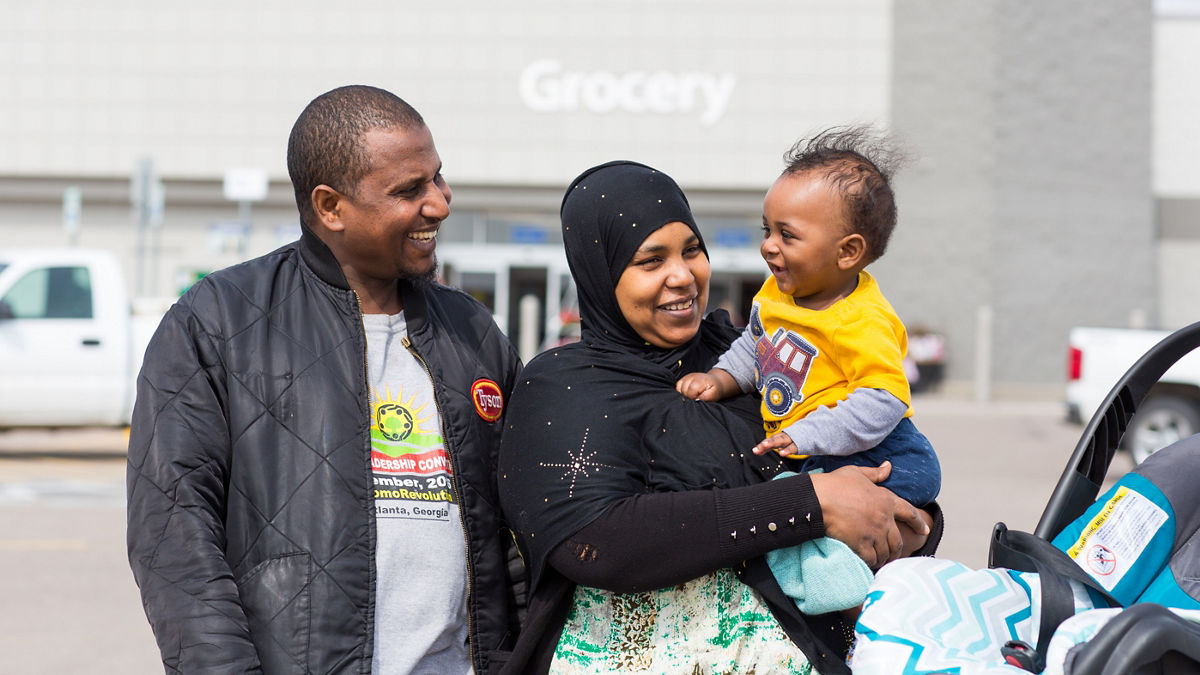 Parents  smiling while holding their toddler.