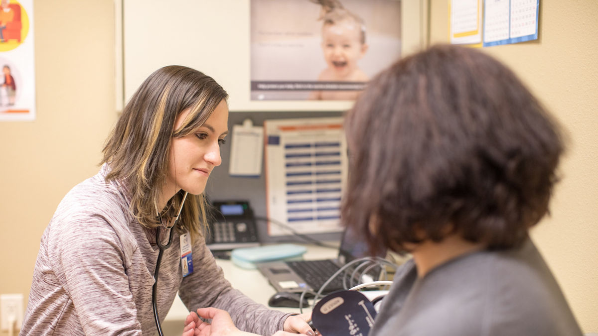 A woman takes a patient's blood pressure.