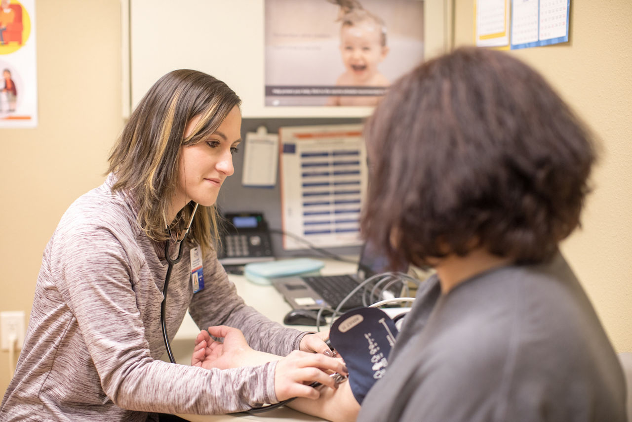 A woman takes a patient's blood pressure.