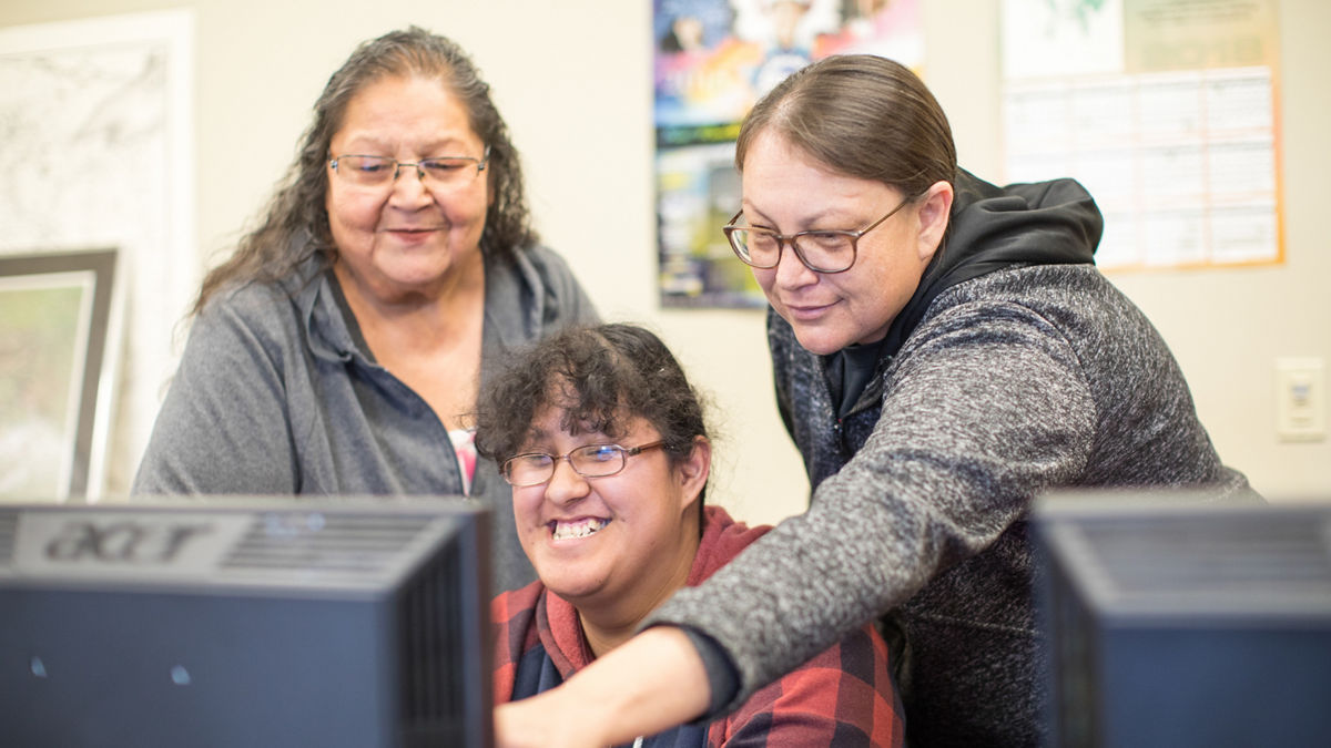 Three women looking at computer screen together.