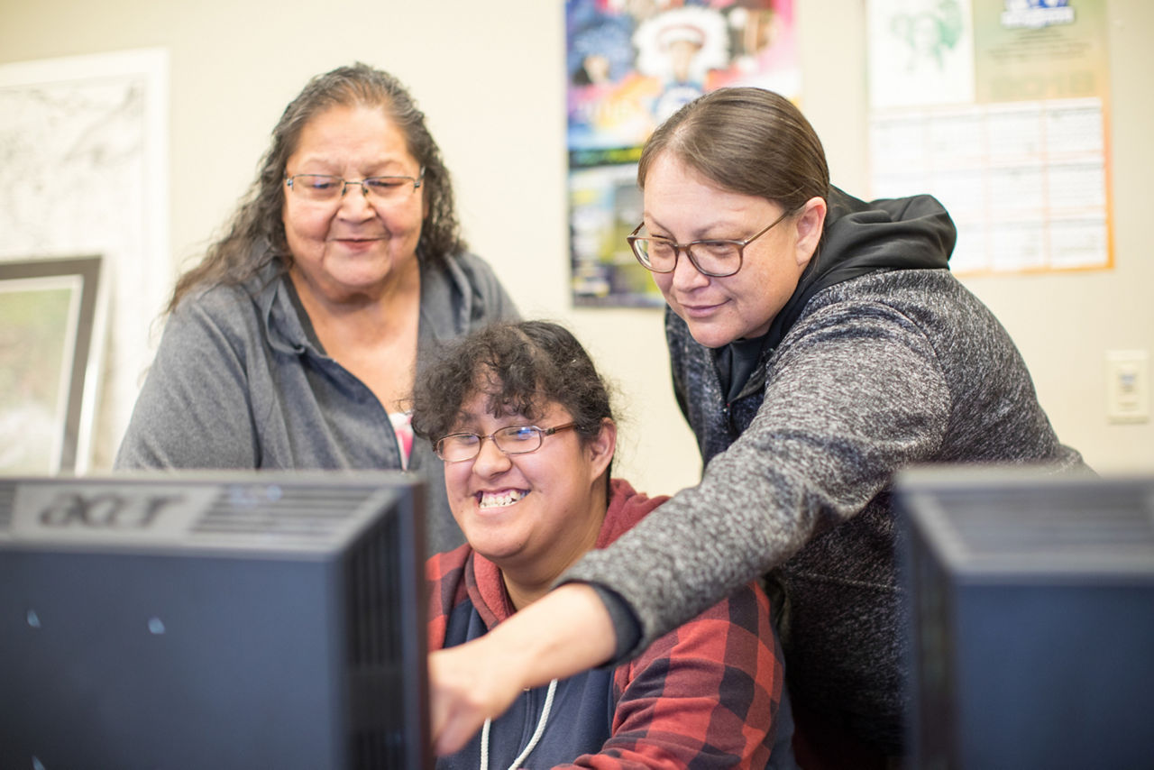 Three women looking at computer screen together.