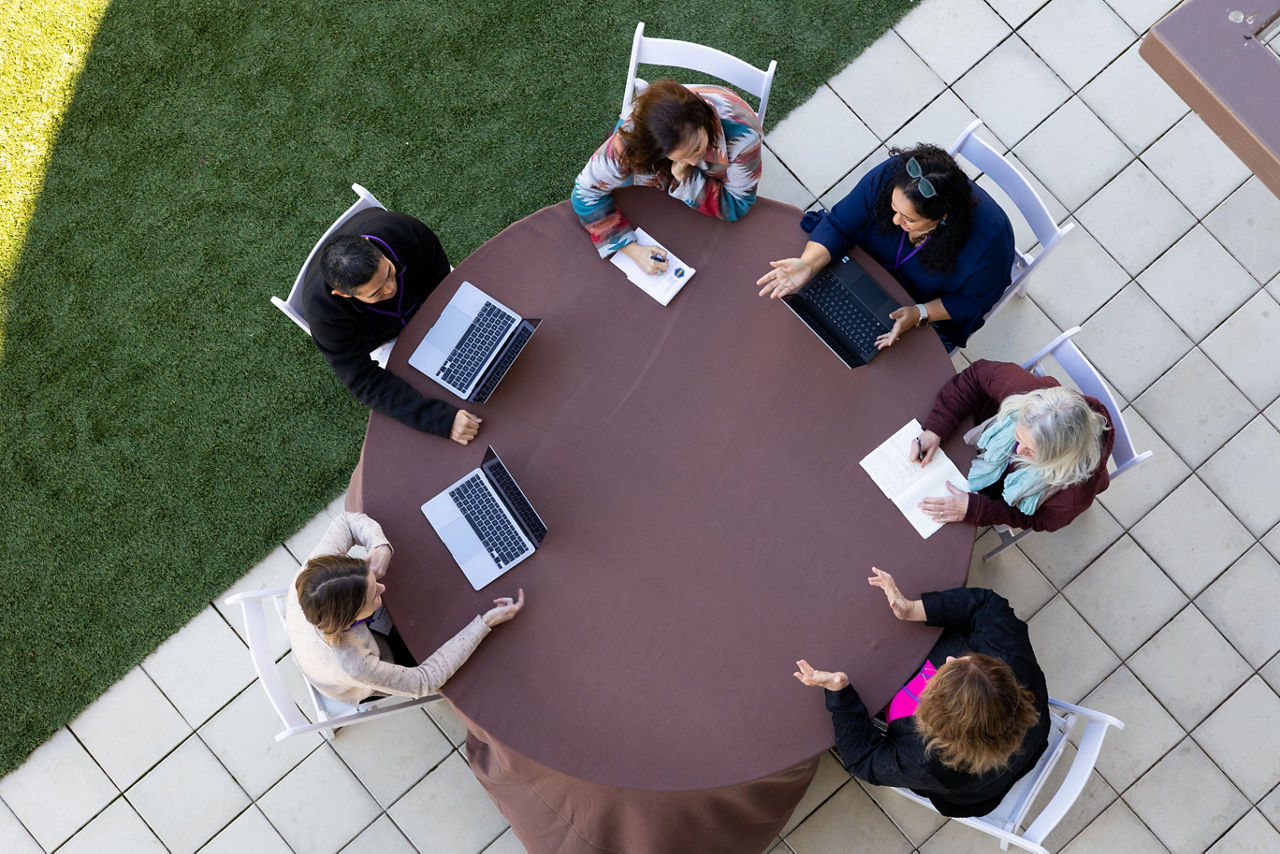 An aerial view of people sitting around a table during a meeting. outside.