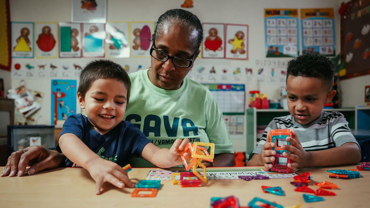 A woman plays a game with two young children.