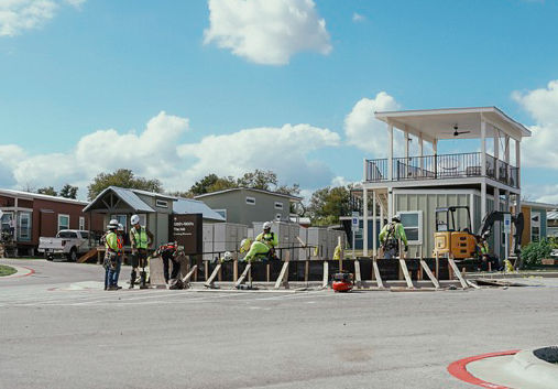A group of men in hard hats working on a construction project under a beautiful blue sky.