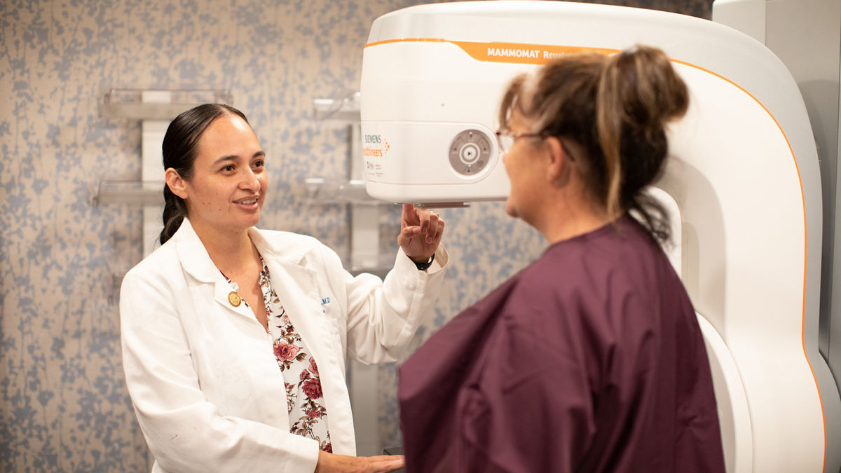 Chairty Reynolds (right) is a full-spectrum family medicine physician and the medical director for Fond du Lac Human Services Division. She is pictured here inside the Min No Aya Win (Human Servces Center) explainig the mammogram device available at their health center. The mission of the Fond du Lac Human Services Division is to elevate the health and social well-being of American Indian people living in the service area through the provision of culturally appropriate services, research, education and employment opportunities.