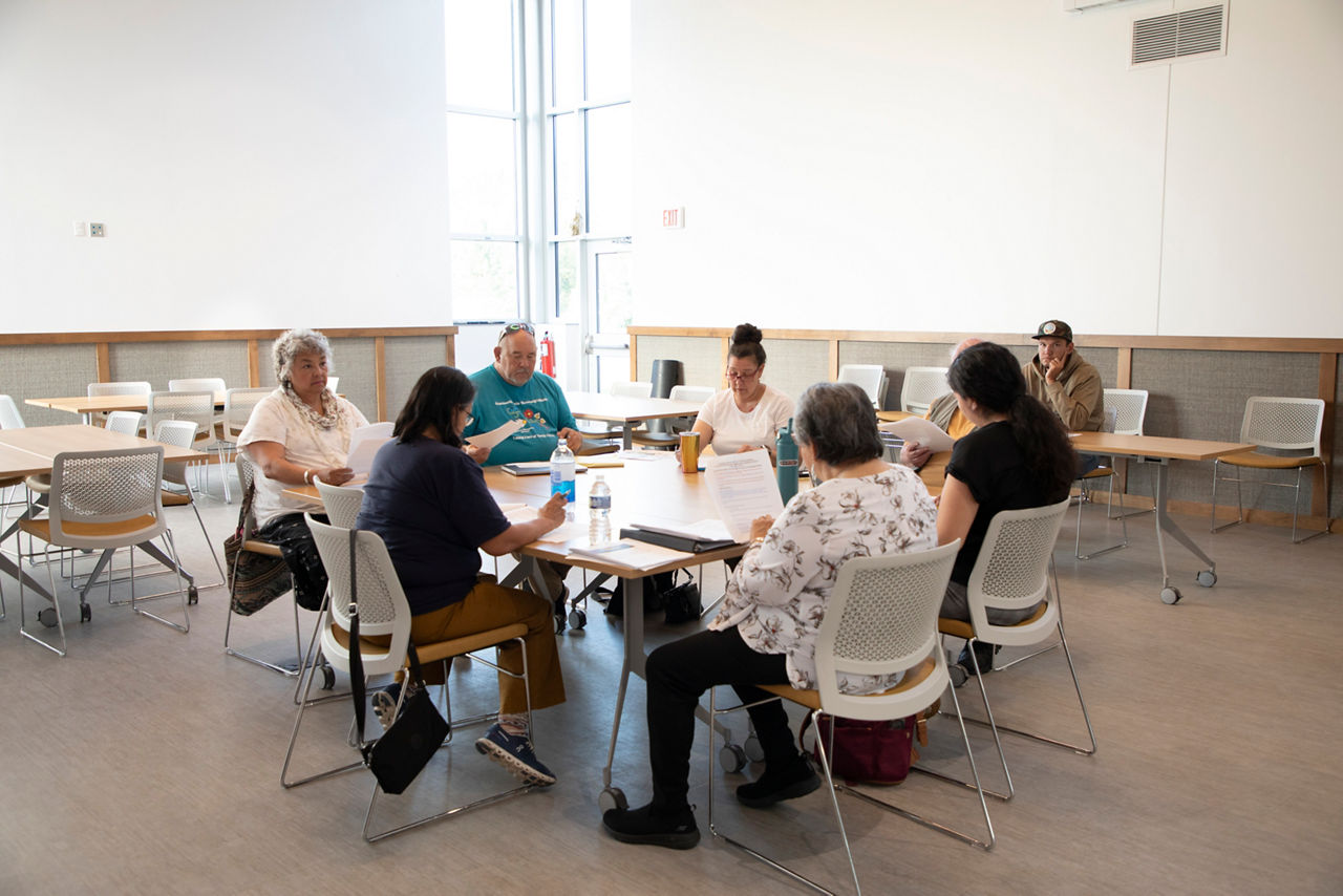 A group of people gathering around a conference table. 