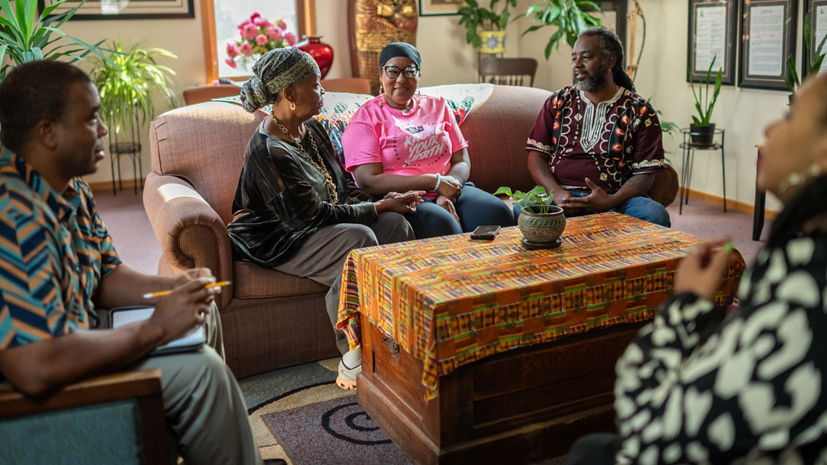 A group of people sitting around a room and talking.