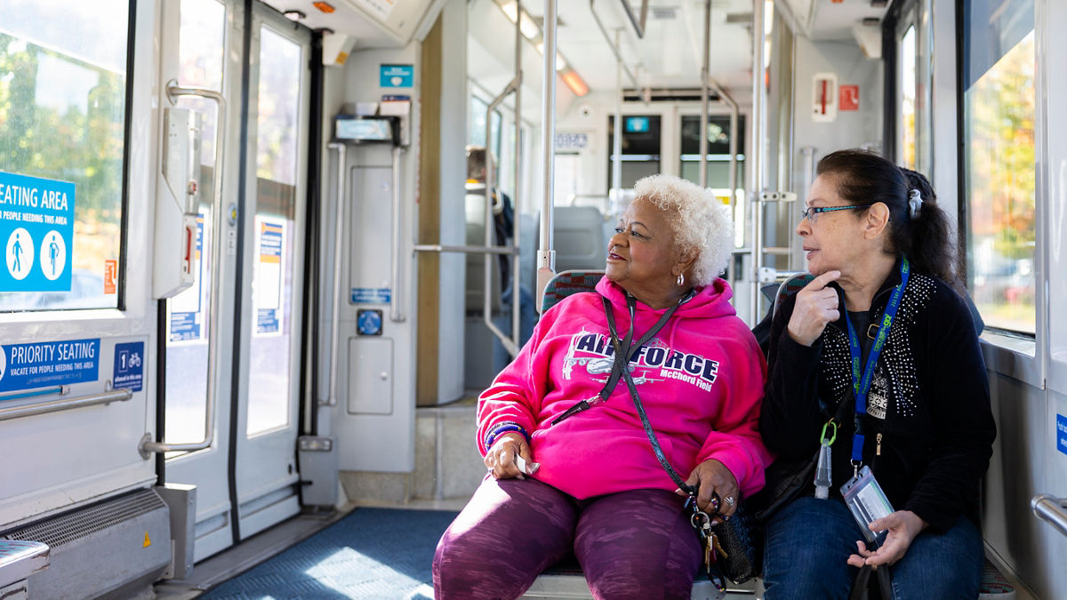 Two people sitting side by side, looking out the window of the Tacoma Link train.