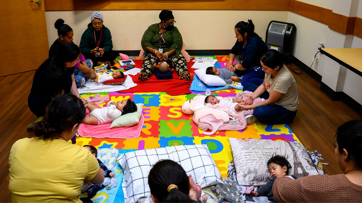 Mothers participate with their children in a baby massage class.