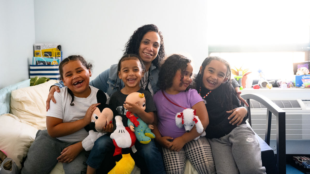 A mother siting on a bed for a portrait with her children.