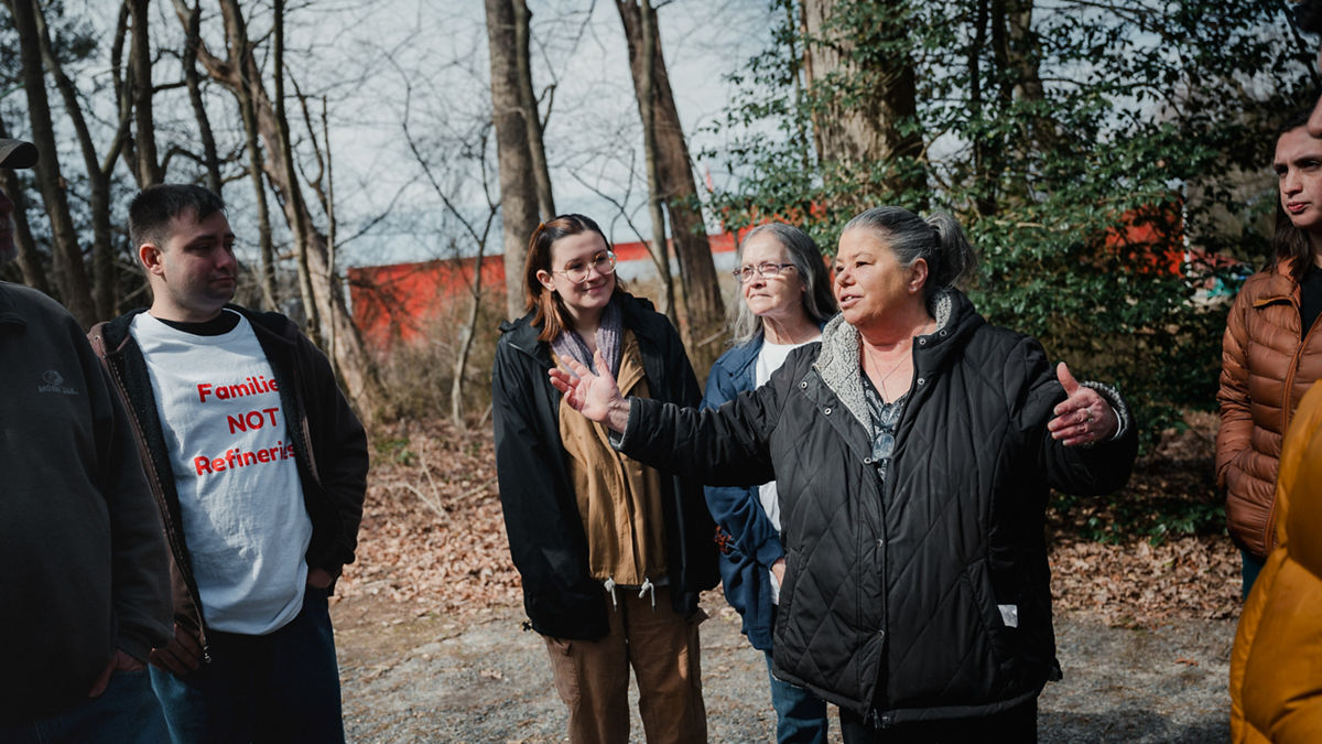A community organizer stands and speaks to a group of residents while they gather around.