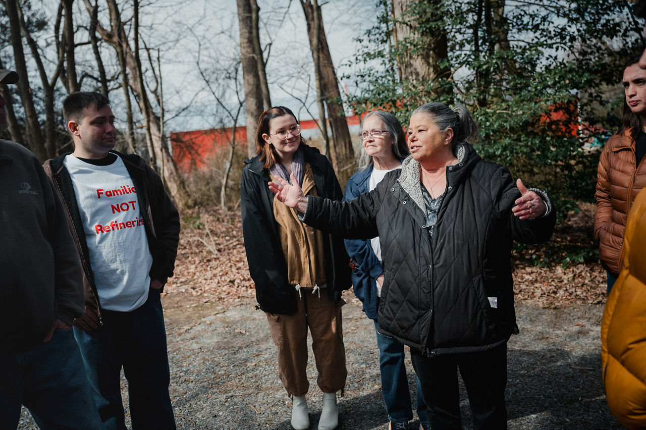 A community organizer stands and speaks to a group of residents while they gather around.