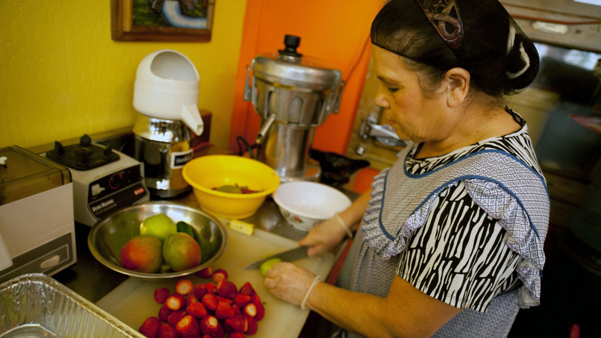 A woman preparing fruit in restaurant kitchen.