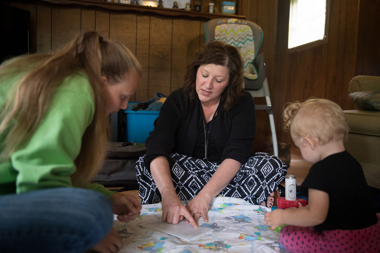 Maria Friend, center, Director of Early Care Programs, visits with Sonya Kisner and her daughter Catherine Ann Kisner, 13 months, in their Oakland, Maryland home as part of Healthy Families Garrett County. The early care program is voluntary for families who wish to participate and targets the developmental years from newborn to three years old. The visiting nurse offers advice, monitors a baby's weight, physical and mental development, and can assist mothers in connecting to county services.