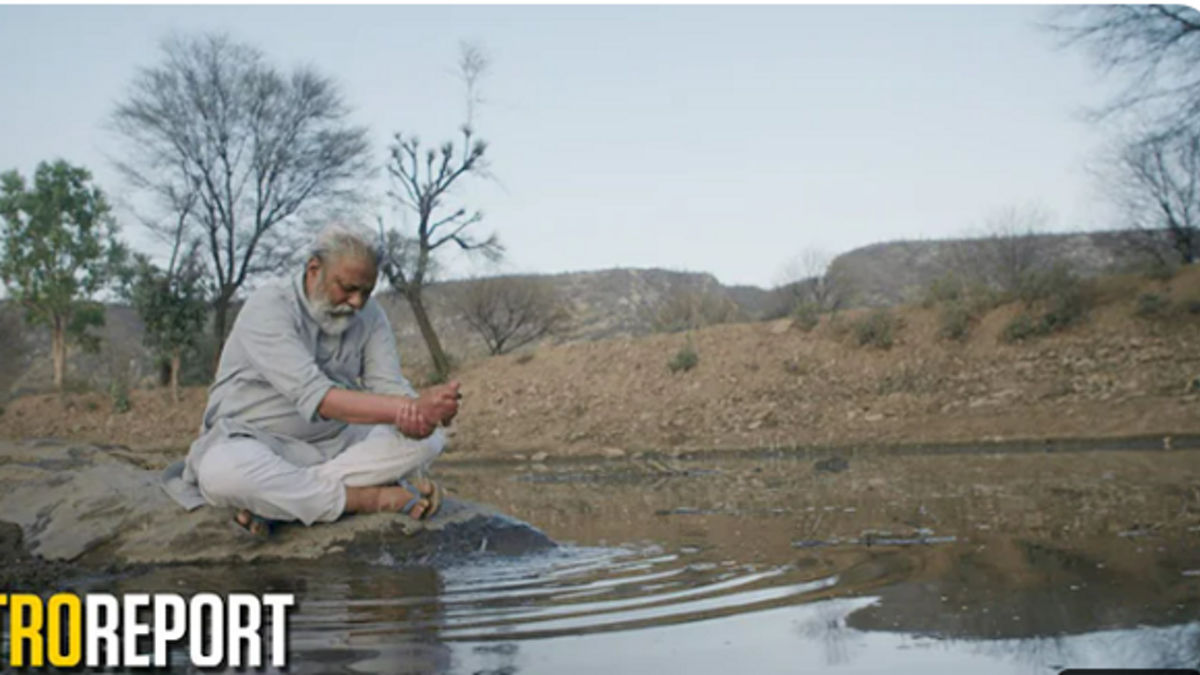 Man sitting at edge of stream.