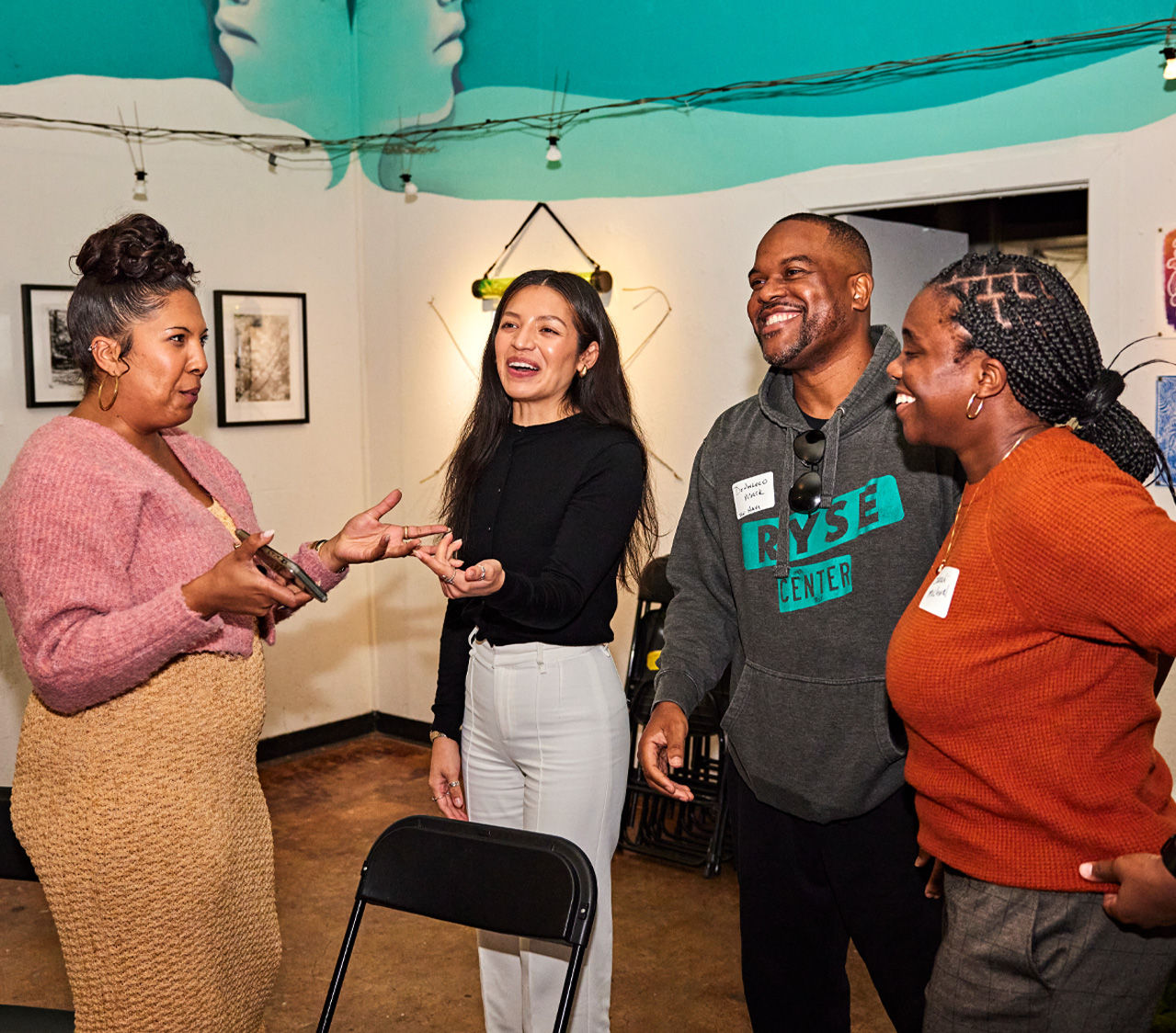 A group of four people standing together, talking.