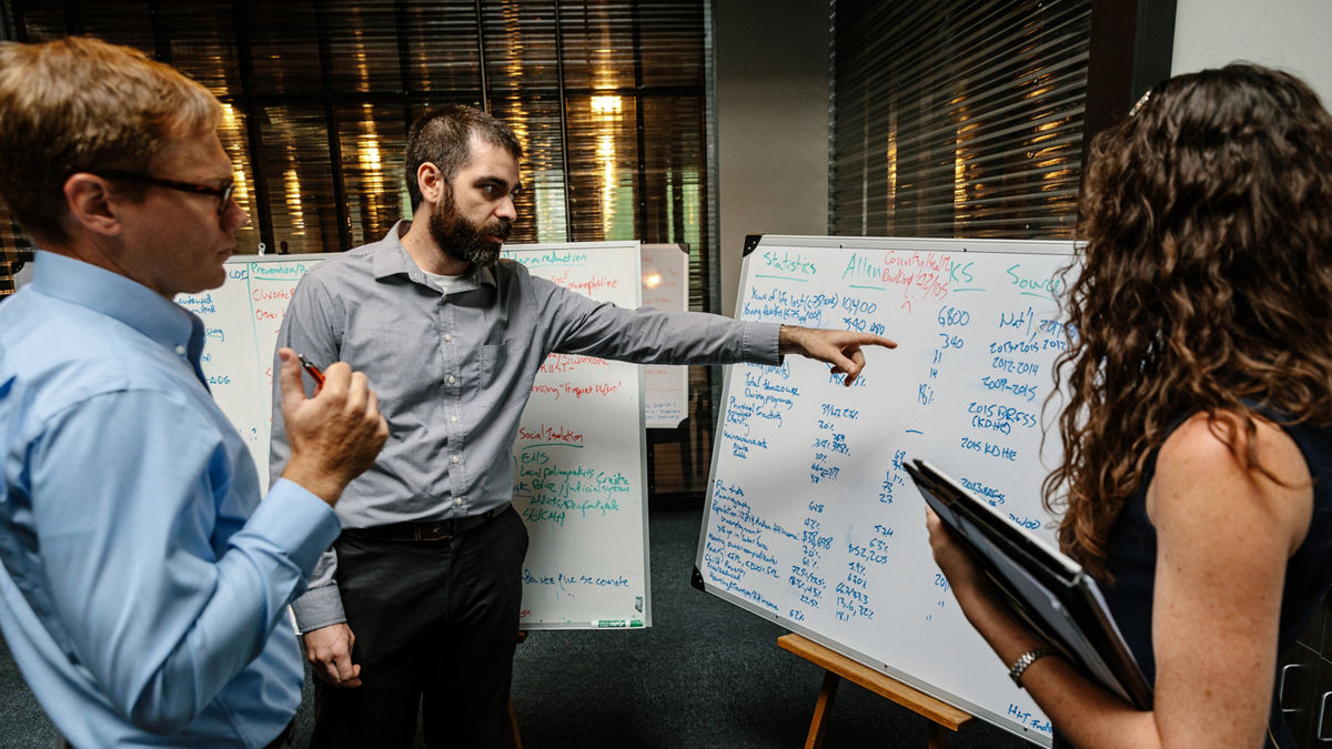 Professionals review information on a white board. 