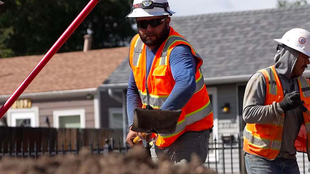 Two people in safety vests working on a residential construction project.