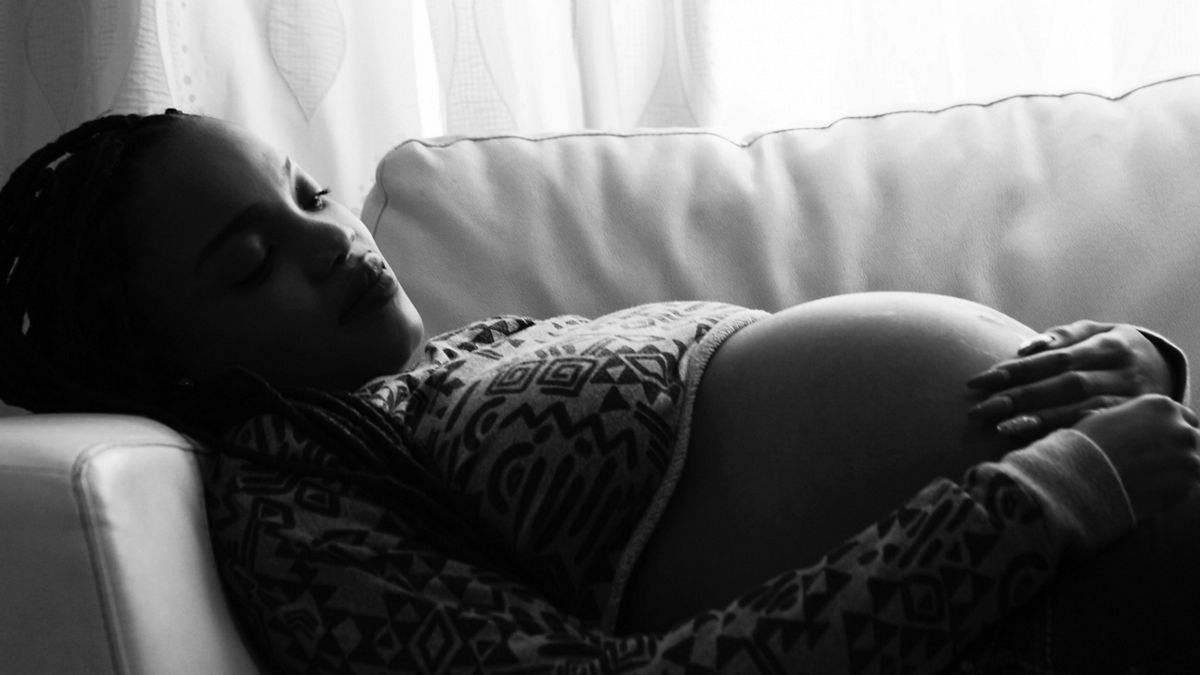 A pregnant person rests on a couch.