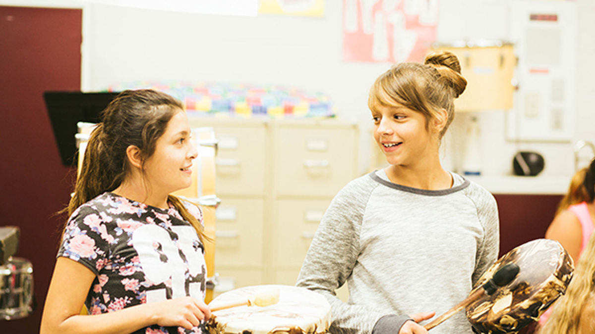 Two young girls playing tambourines.