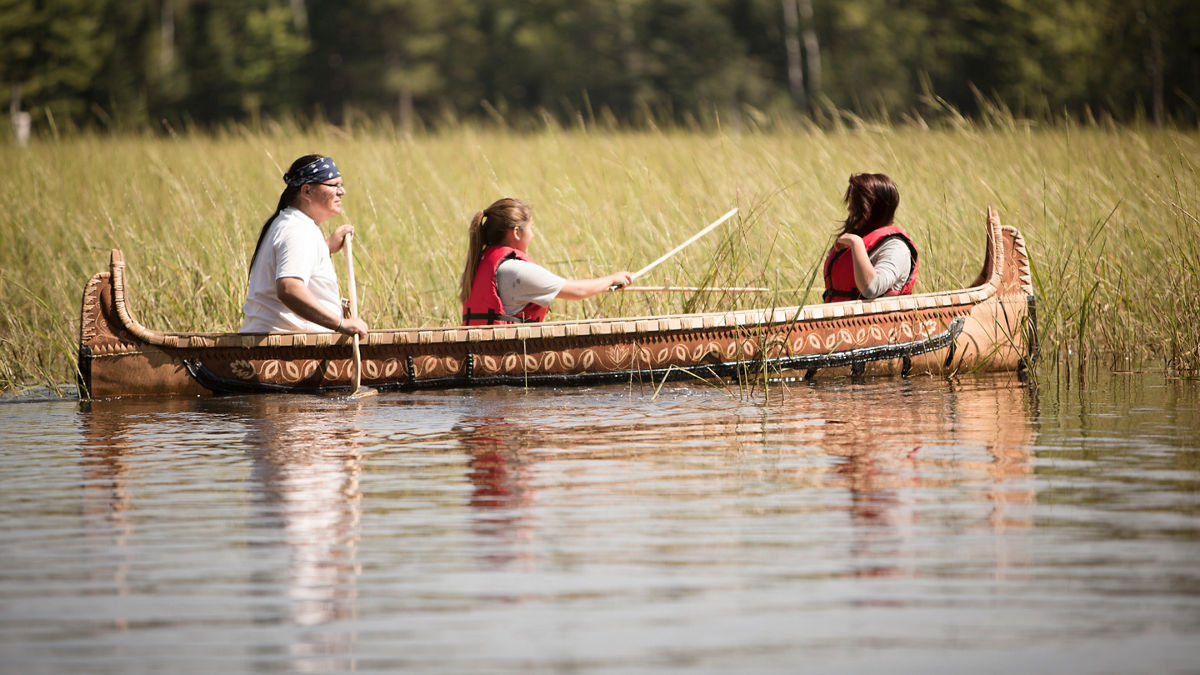 A family canoeing to harvest wild rice.