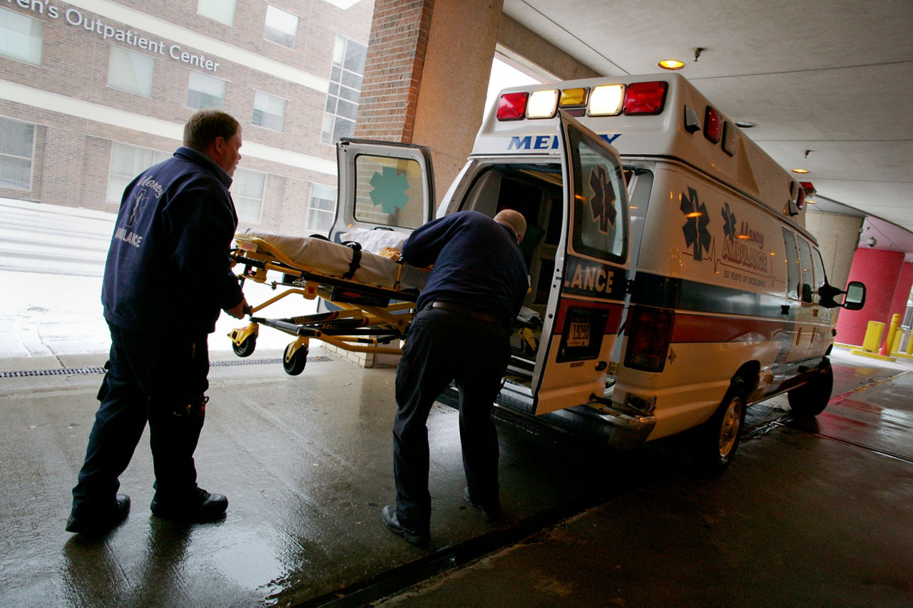 Paramedics load a gurney into an ambulance.