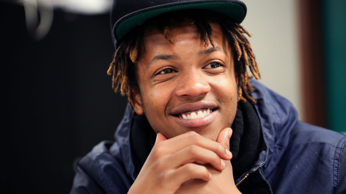 A young man in a baseball cap smiling.