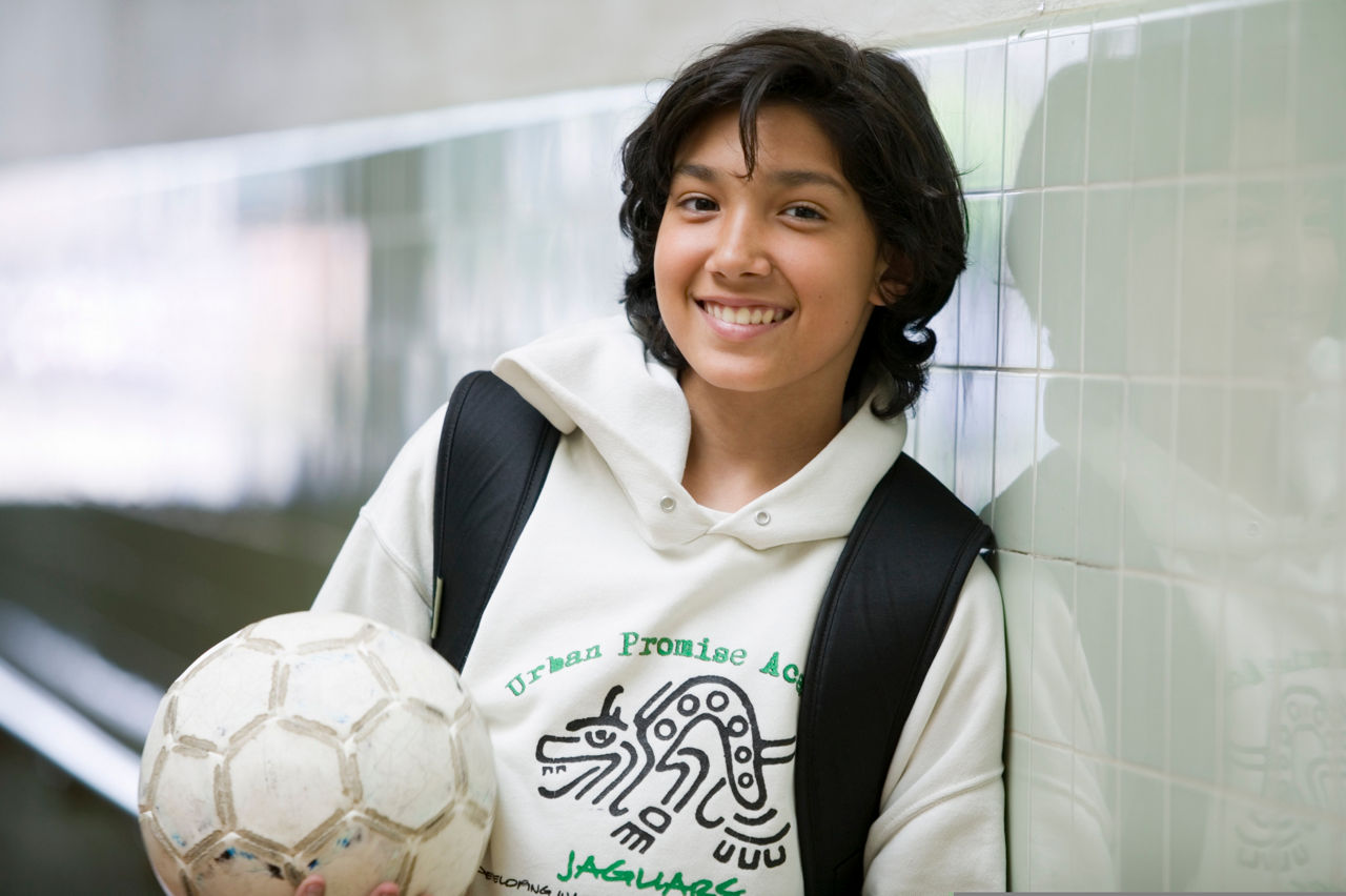 Sports 4 Kids junior coach Christian Olivales in the hallway of Urban Promise Academy, Oakland, California.  Sports 4 Kids (Playworks)