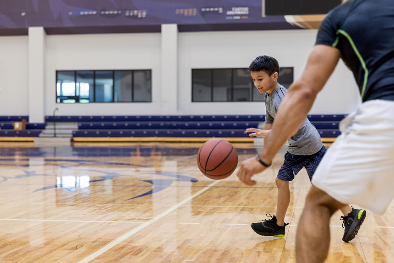 An elementary age boy dribbles a basketball on the school basketball court.