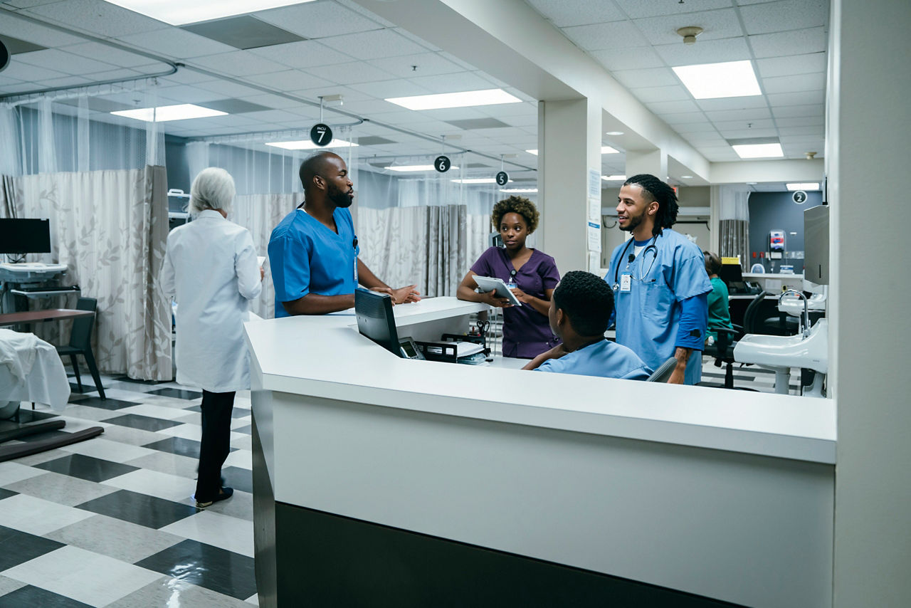 Doctors and nurses conversing in a hospital reception area.