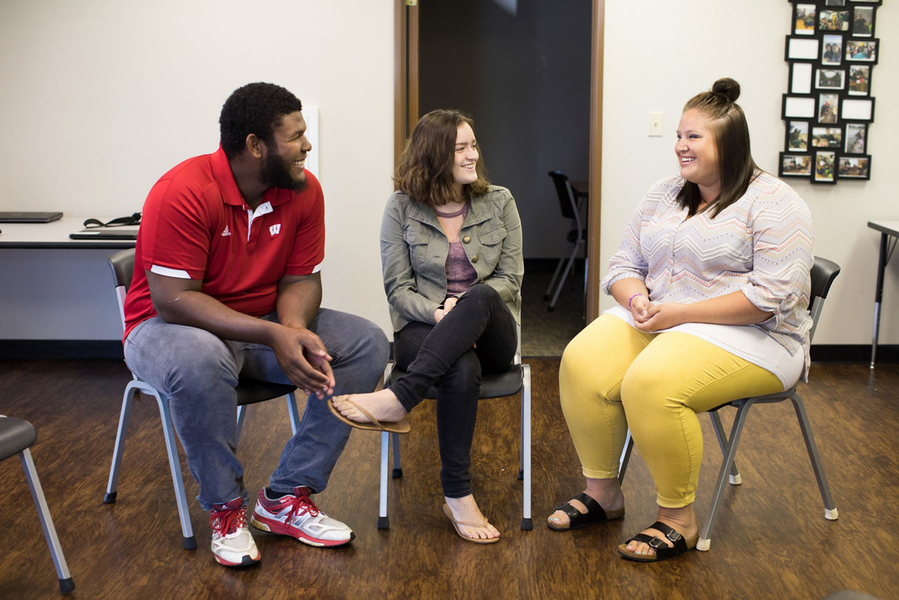 Three students talking in a classroom.