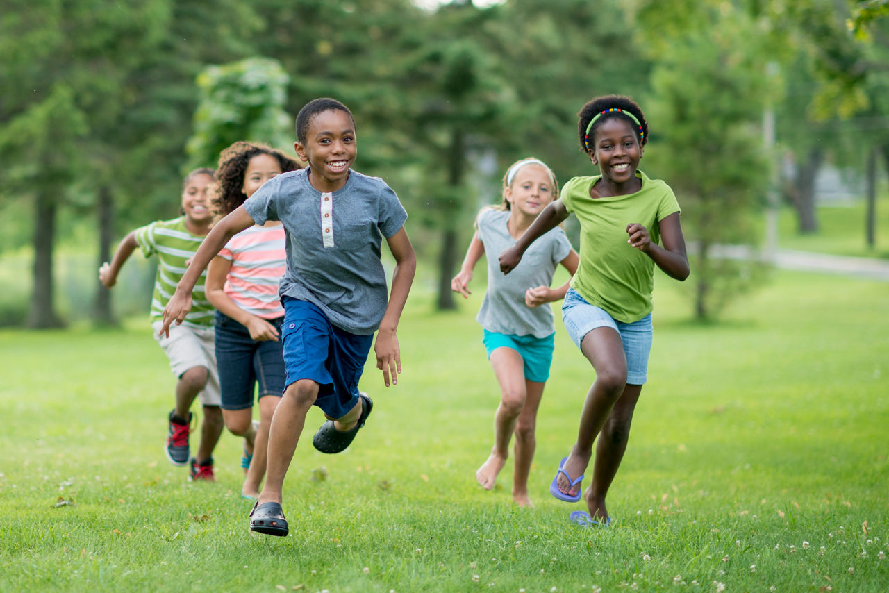 Boys and girls run and play in the park.