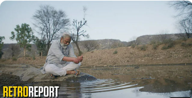 Man sitting at edge of stream.