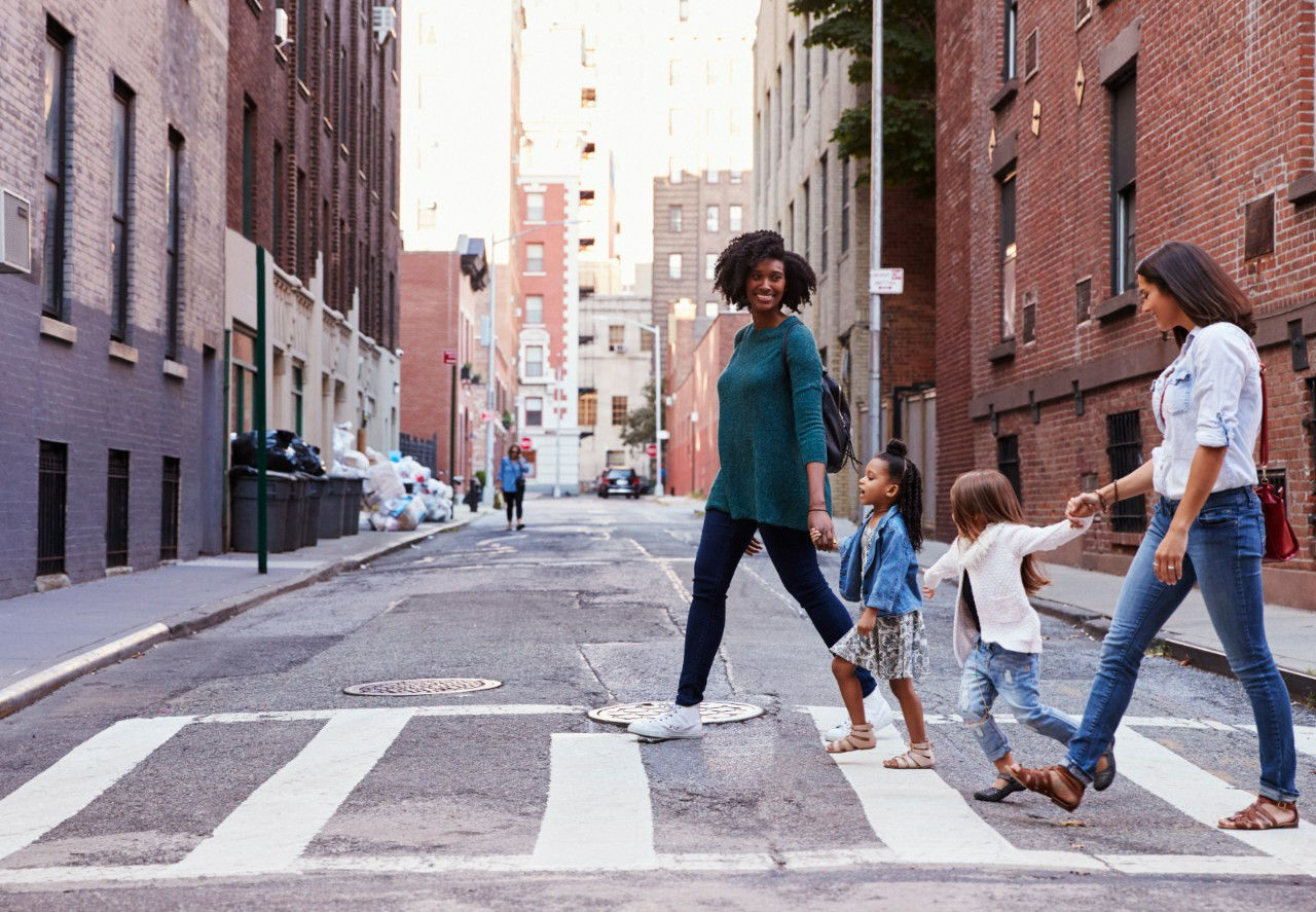 Two mother friends with two daughters crossing the road.